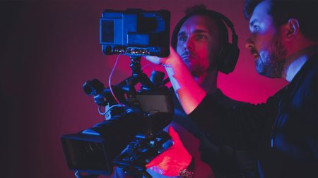 Videographer using editing software to assemble footage into cohesive final result, color correcting it to ensure project meets desired aesthetic, working in creative studio